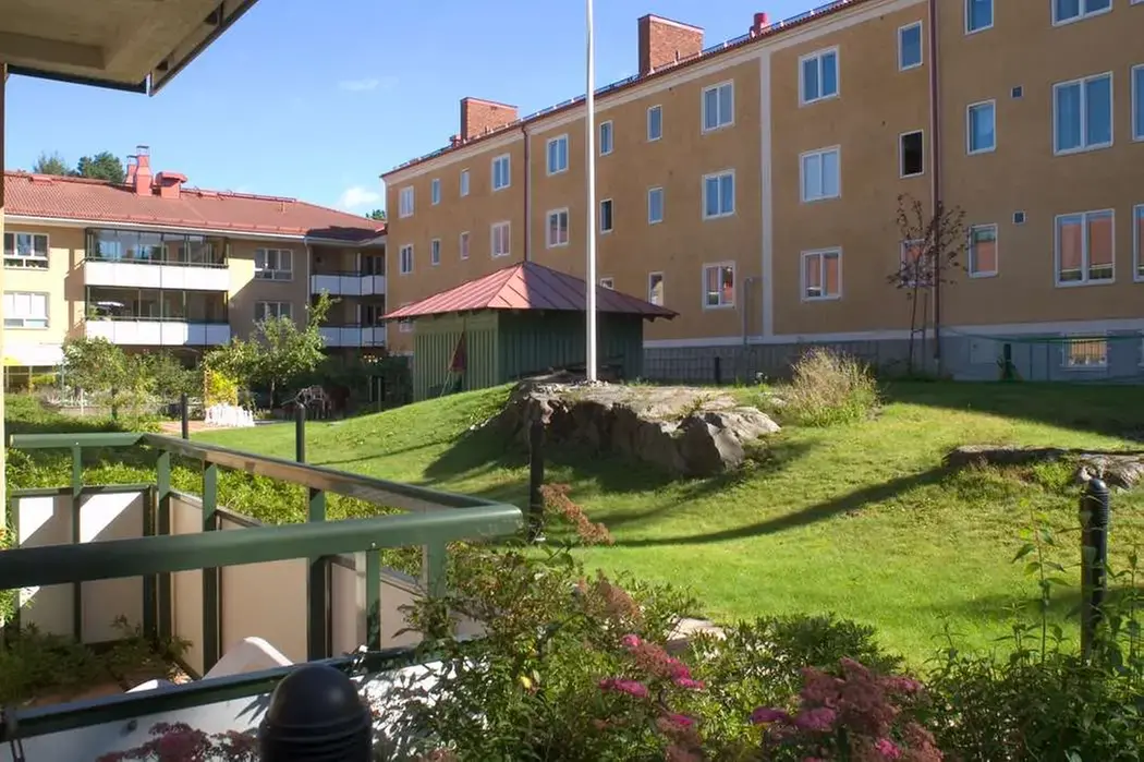 Fastigheten Brevlådan 1 på Brevvägen 8-14 i Enskede. Bilden visar fasad samt en gräsmatta mellan husen.